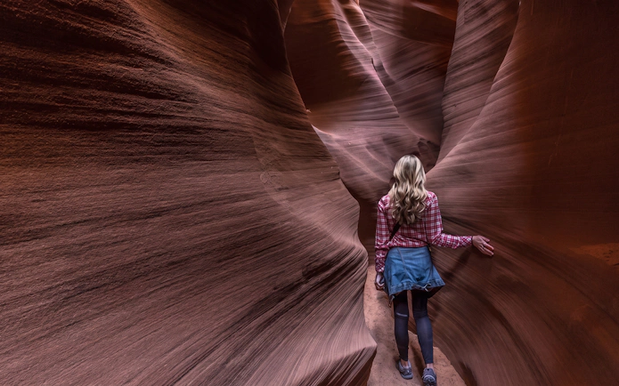 Visitor exploring narrow sandstone passage in Secret Antelope Canyon tour.