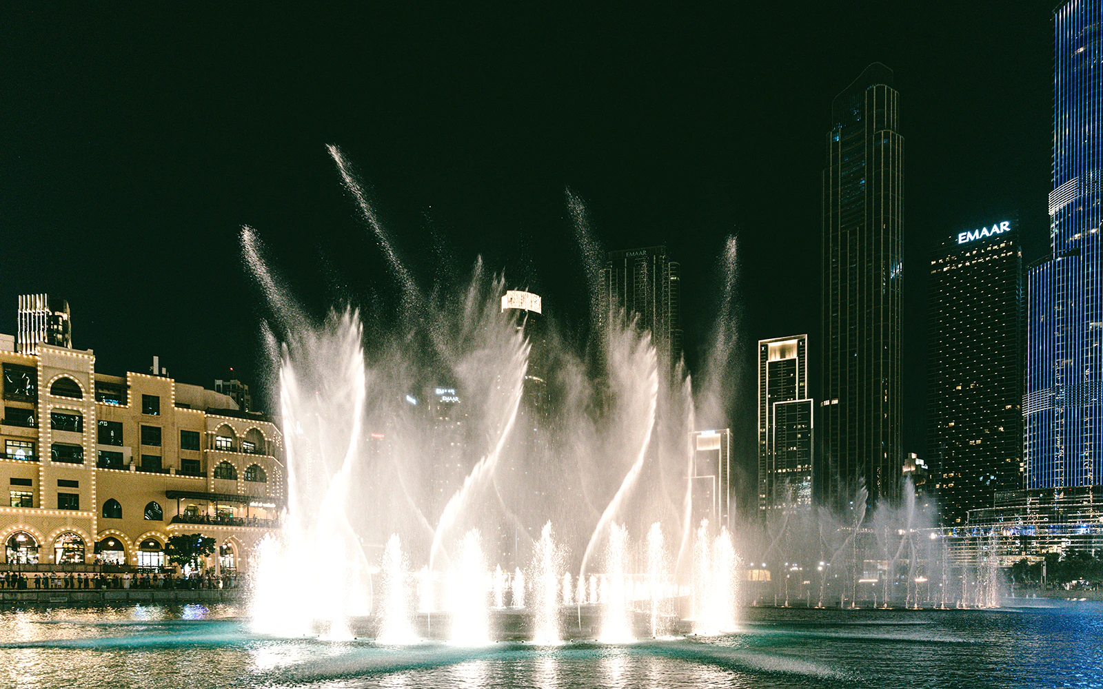 Dubai Fountain night show with illuminated skyscrapers in the background.