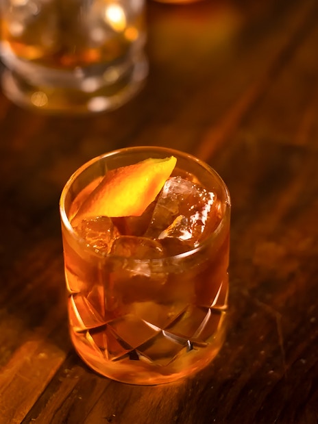 Jameson whiskey cocktail with orange peel garnish on a wooden table.