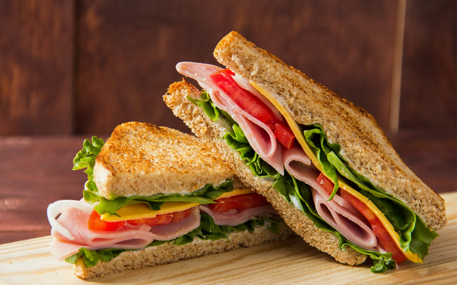 Ham and cheese sandwich with lettuce and tomato on whole grain bread.