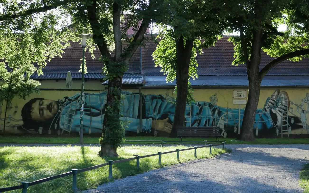 Street art mural of a reclining figure in a Zagreb park, part of the self-guided city exploration game.