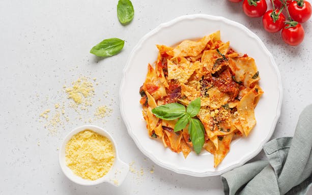 Maltagliati fresh pasta being prepared on a wooden table in an Italian kitchen.