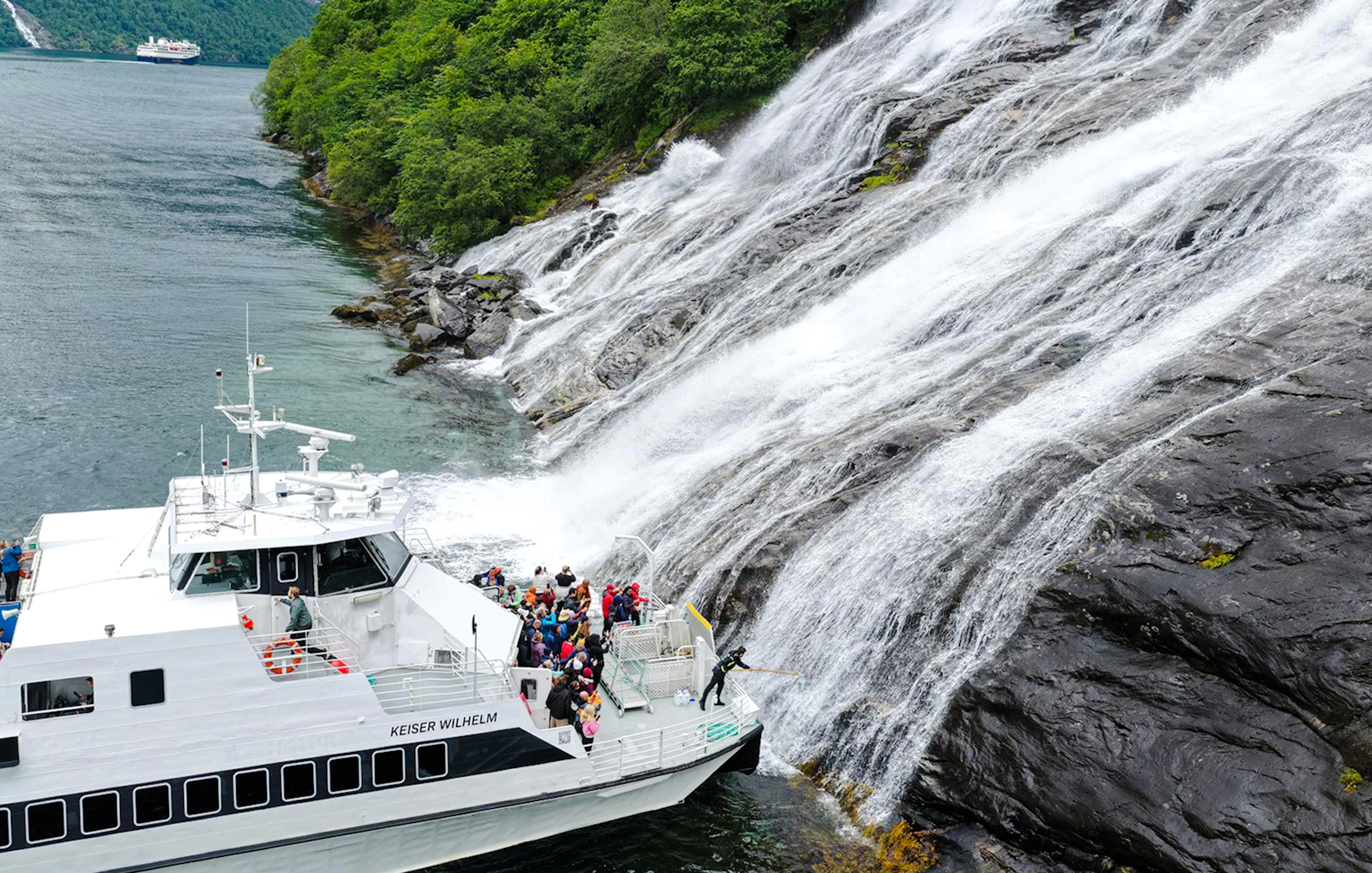 Boat with people near the Bachelor Waterfall in Geiranger Fjord, Norway.