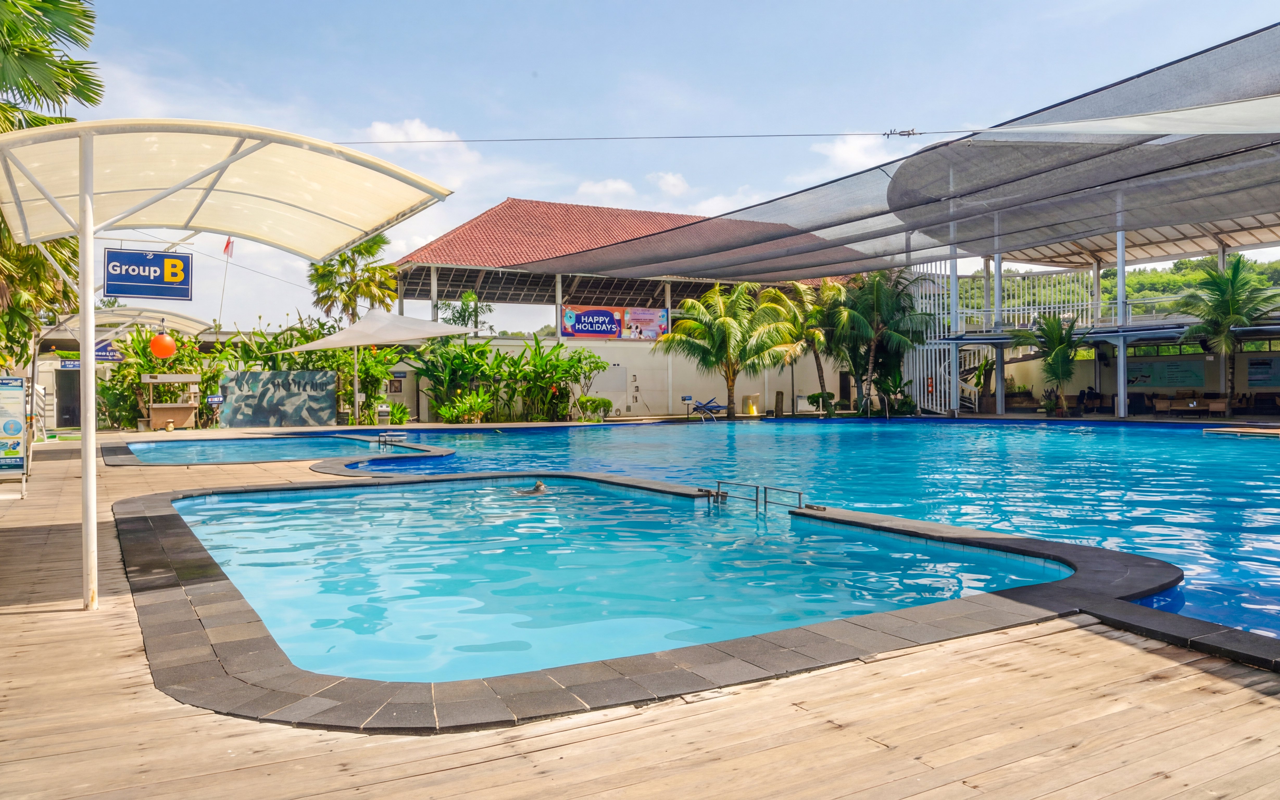 Outdoor pool area at Bali Exotic Marine Park with shaded seating and tropical plants.