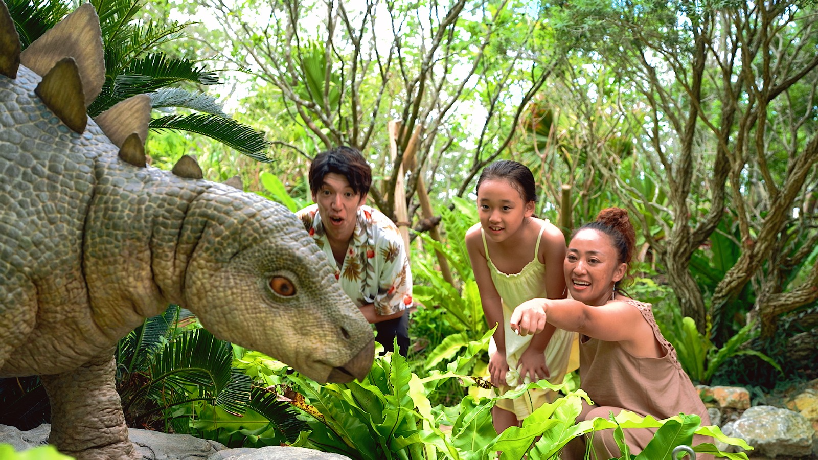 Visitors interacting with a dinosaur exhibit at JUNGLIA OKINAWA Park.