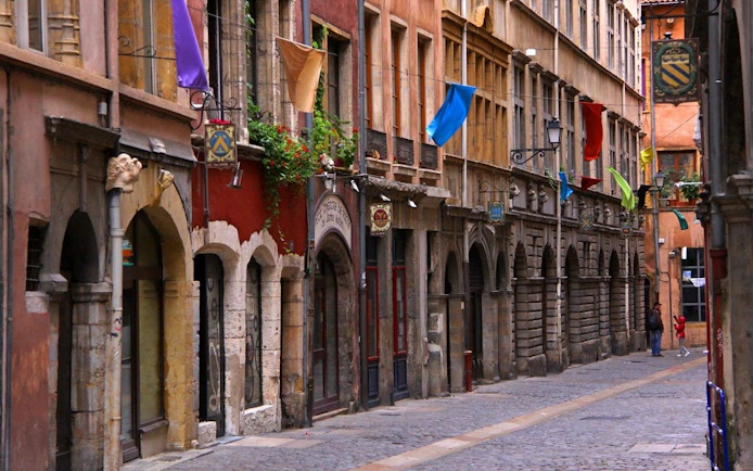 Lyon Old Town street with colorful flags and historic stone buildings.