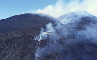 Aerial view of Mount Etna with smoke rising from volcanic craters in Sicily, Italy.