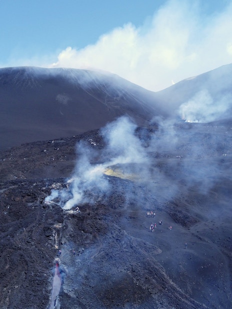 Aerial view of Mount Etna with smoke rising from volcanic craters in Sicily, Italy.