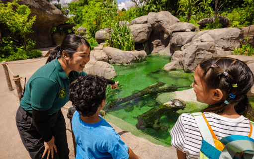 Ranger explaining pond ecosystem to children at entrance pond.