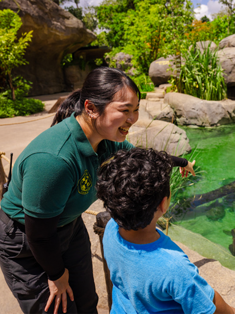 Ranger explaining pond ecosystem to children at entrance pond.