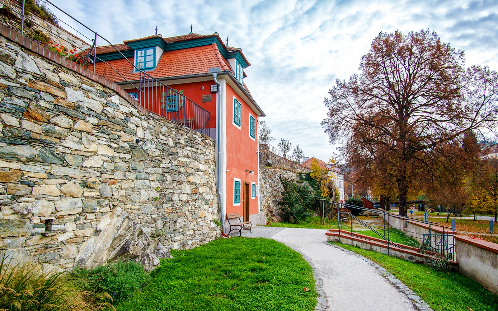 Egon Schiele garden studio with stone wall and path in Cesky Krumlov.