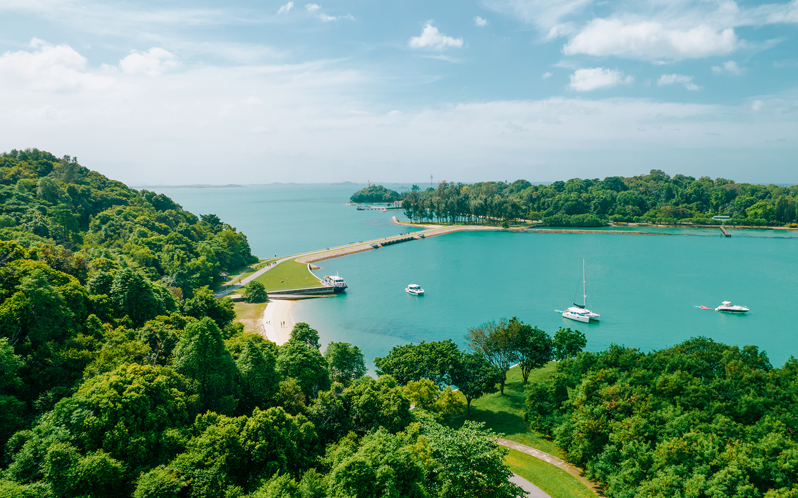 Aerial view of Seringat Island with lush greenery, sandy beaches, and boats in turquoise waters.
