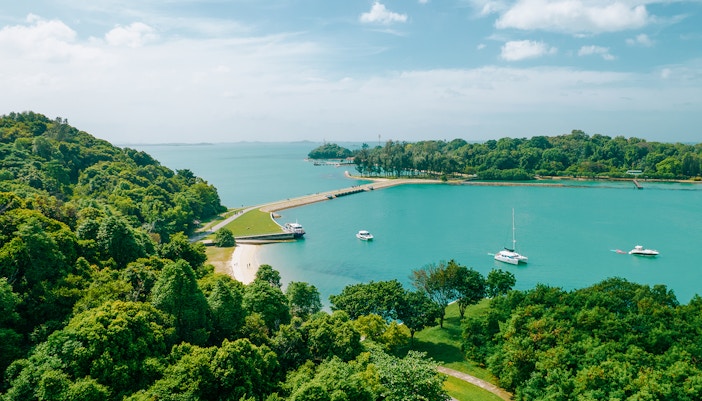 Aerial view of Seringat Island with lush greenery, sandy beaches, and boats in turquoise waters.