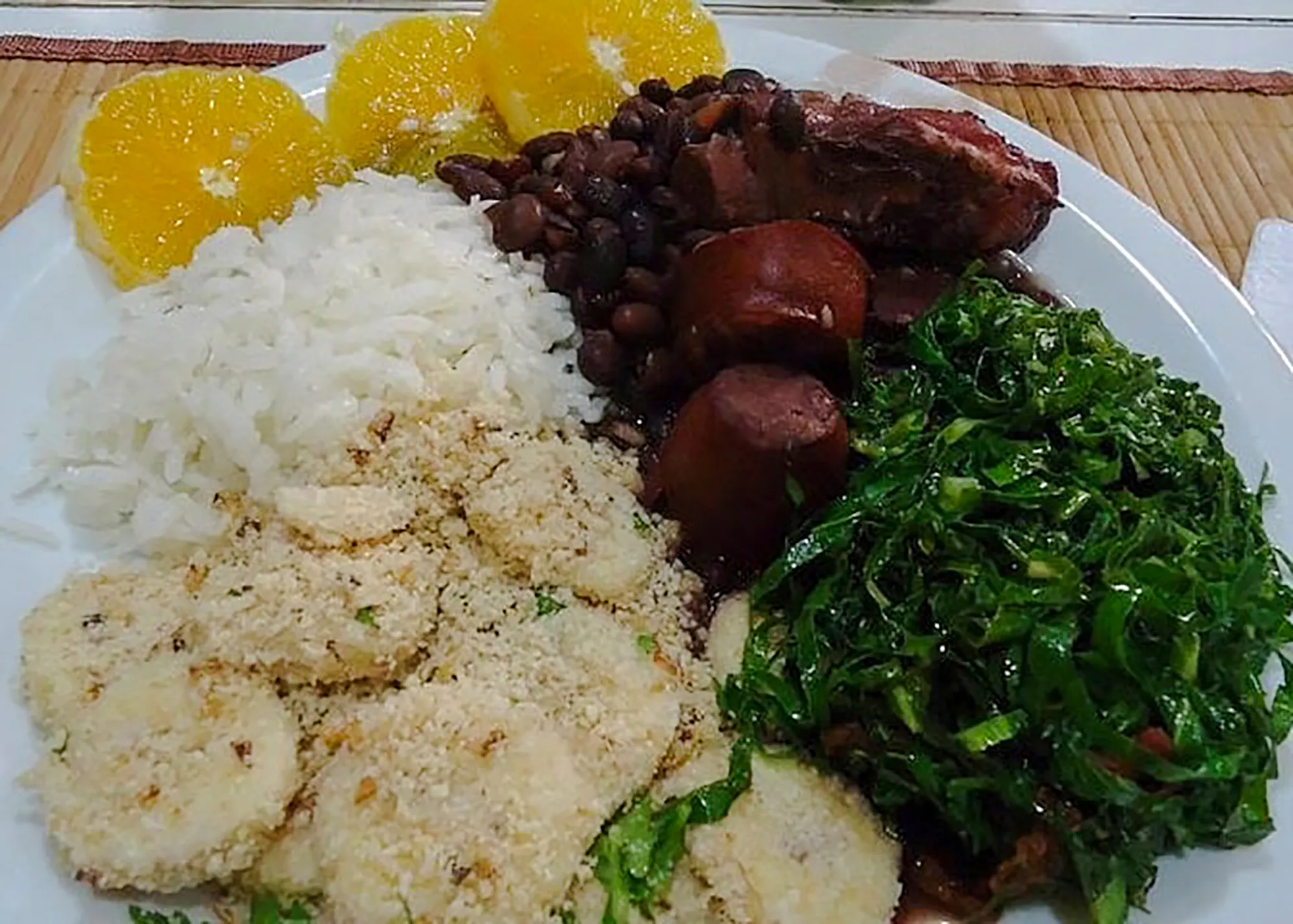Brazilian feijoada with rice, greens, and oranges served in a Copacabana cooking class, Rio de Janeiro.