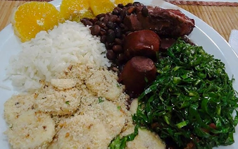 Brazilian feijoada with rice, greens, and oranges served in a Copacabana cooking class, Rio de Janeiro.
