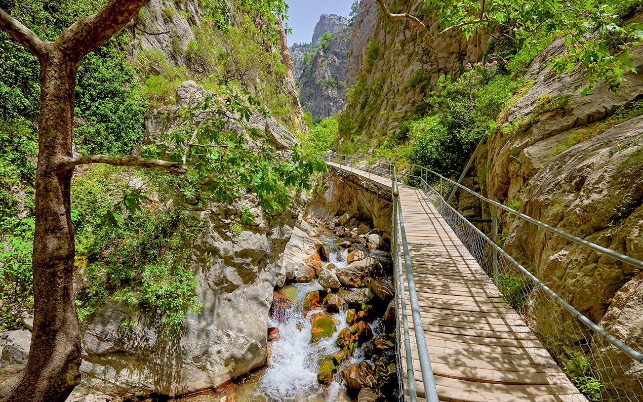 Wooden walkway through a rocky canyon with a stream, Antalya family rafting tour.