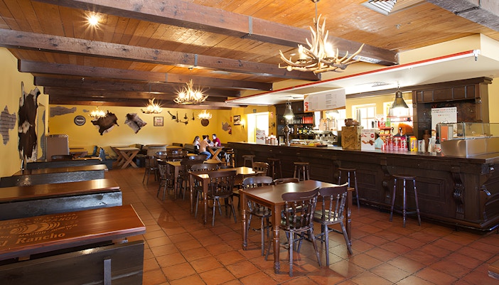 El Coyote Solitario Saloon interior at Parque Warner Madrid, featuring rustic decor and dining tables.