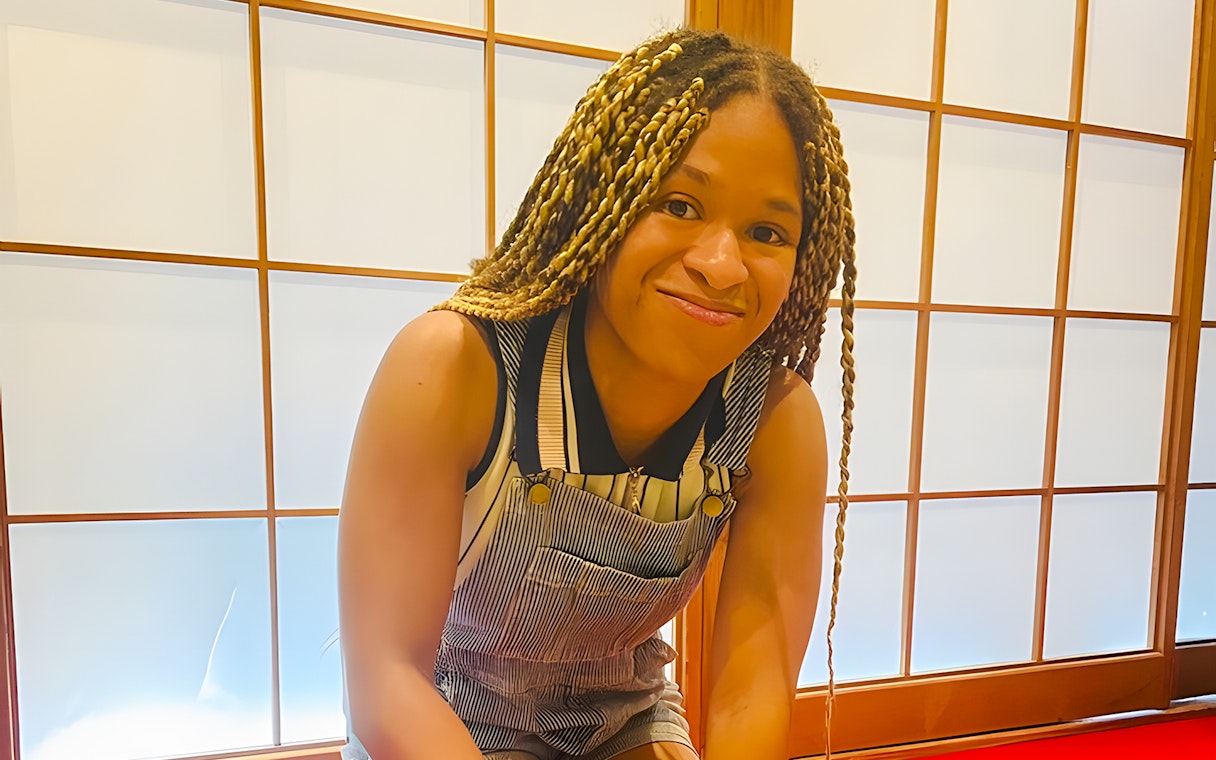 Young girl smiling in front of a traditional Japanese shoji screen.