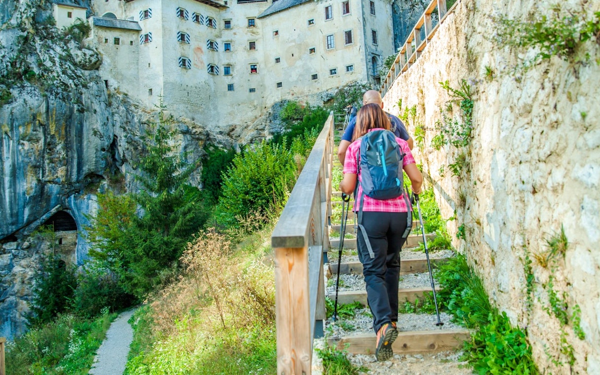 Couple hiking towards Predjama Castle in Slovenia.