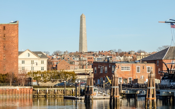 Bunker Hill Monument viewed from the harbor with historic brick buildings in Boston.