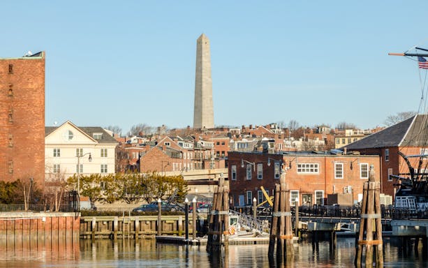 Bunker Hill Monument viewed from Boston Harbor with sailboats in the foreground.