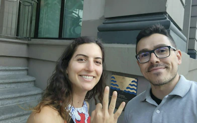 Two people smiling in front of a historical plaque during a self-guided tour in Vancouver's Gastown.