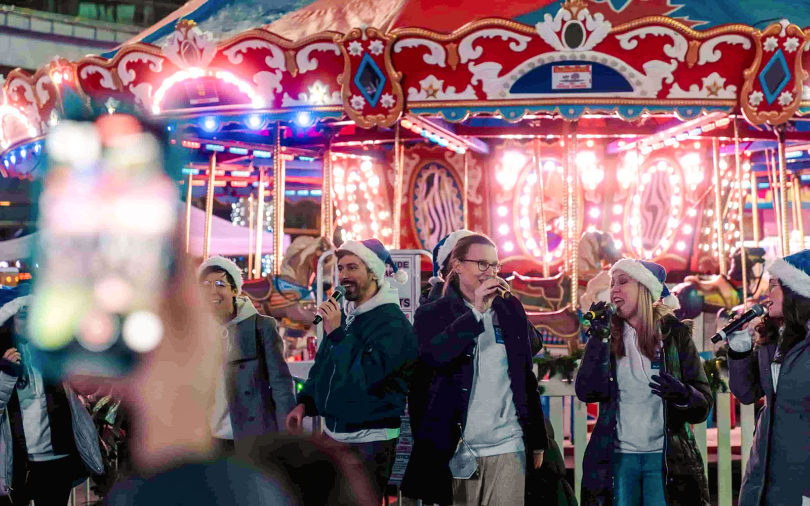 Singers performing at Winter Glow festival in front of a carousel at Sankofa Square.