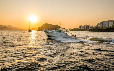 Tourists on a boat during Rio de Janeiro sunset cruise with city skyline in background.