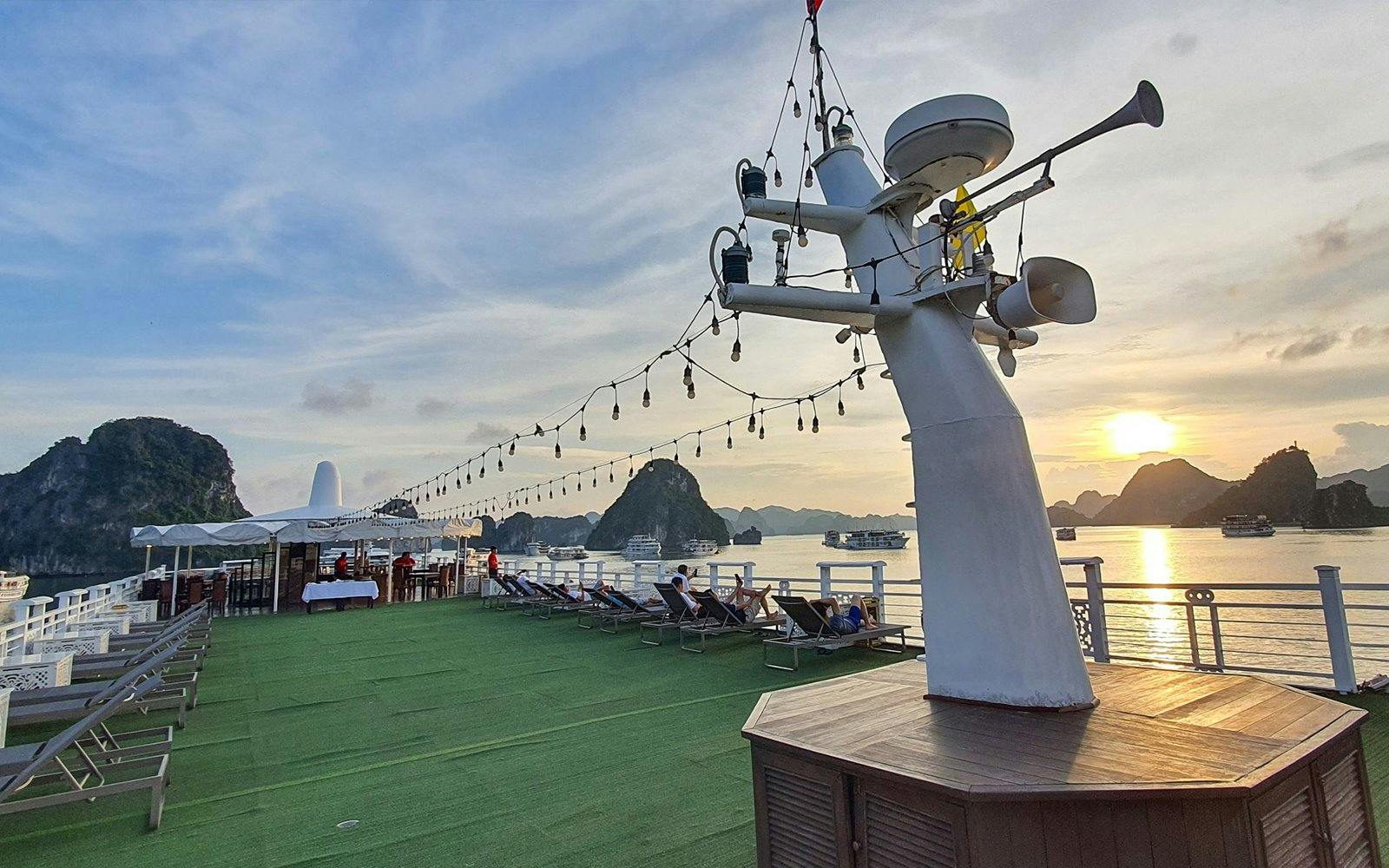 Starlight Cruise deck with lounge chairs and sunset view over Halong Bay.