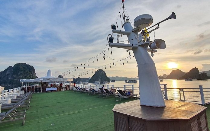 Starlight Cruise deck with lounge chairs and sunset view over Halong Bay.