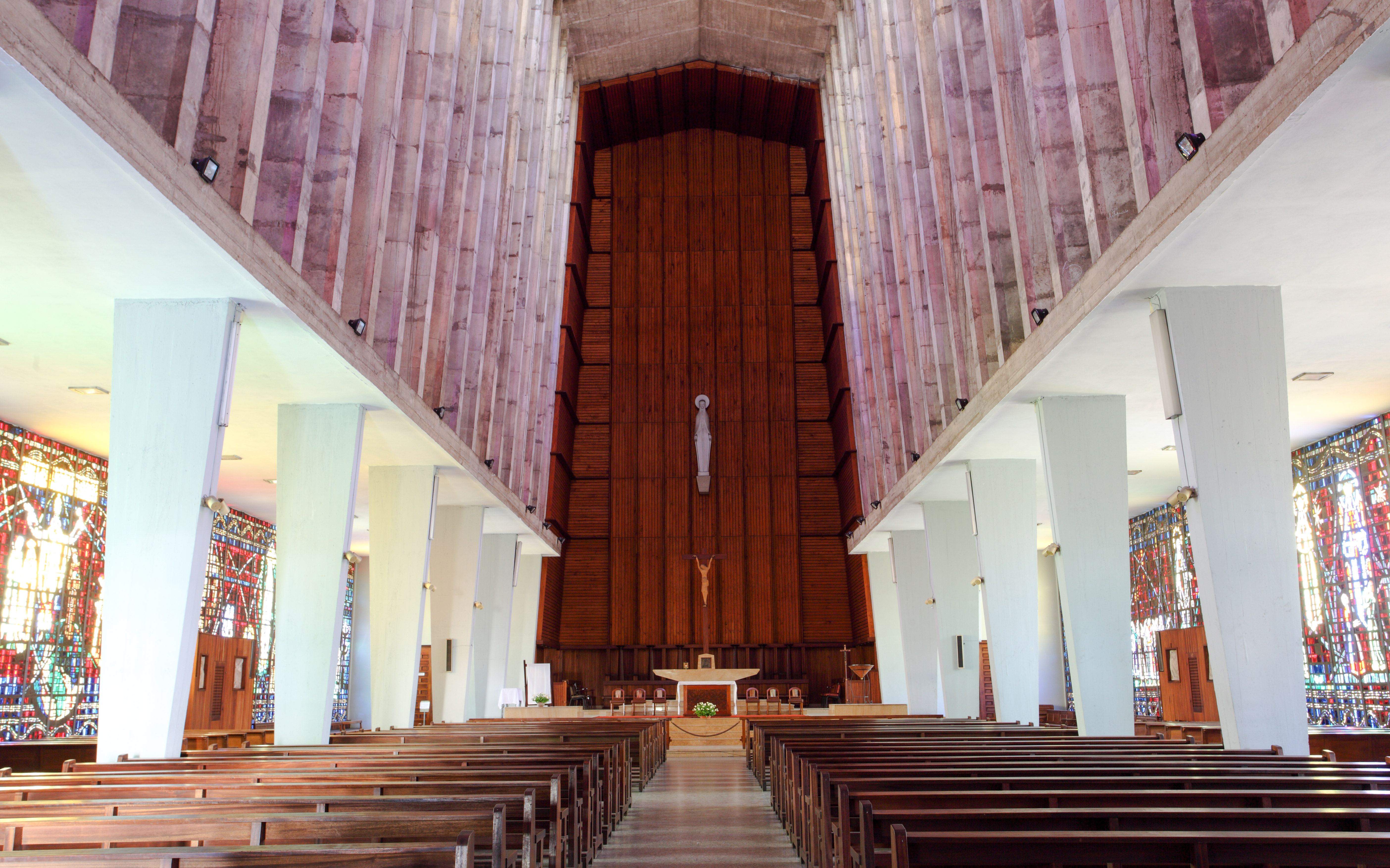 Interior of Church of Notre Dame de Lourdes, Casablanca, featuring stained glass windows and wooden pews.