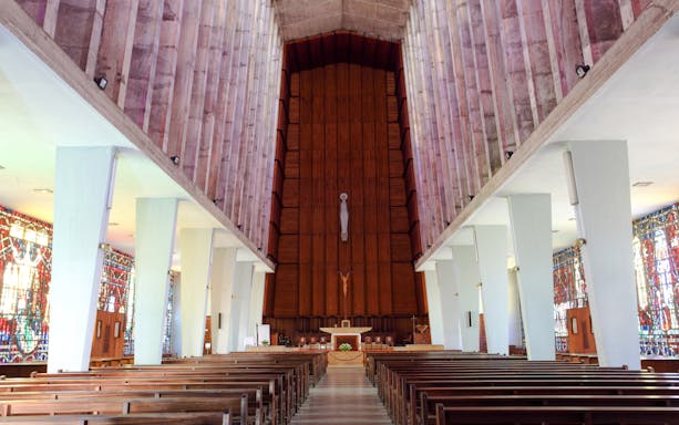 Interior of Church of Notre Dame de Lourdes, Casablanca, featuring stained glass windows and wooden pews.