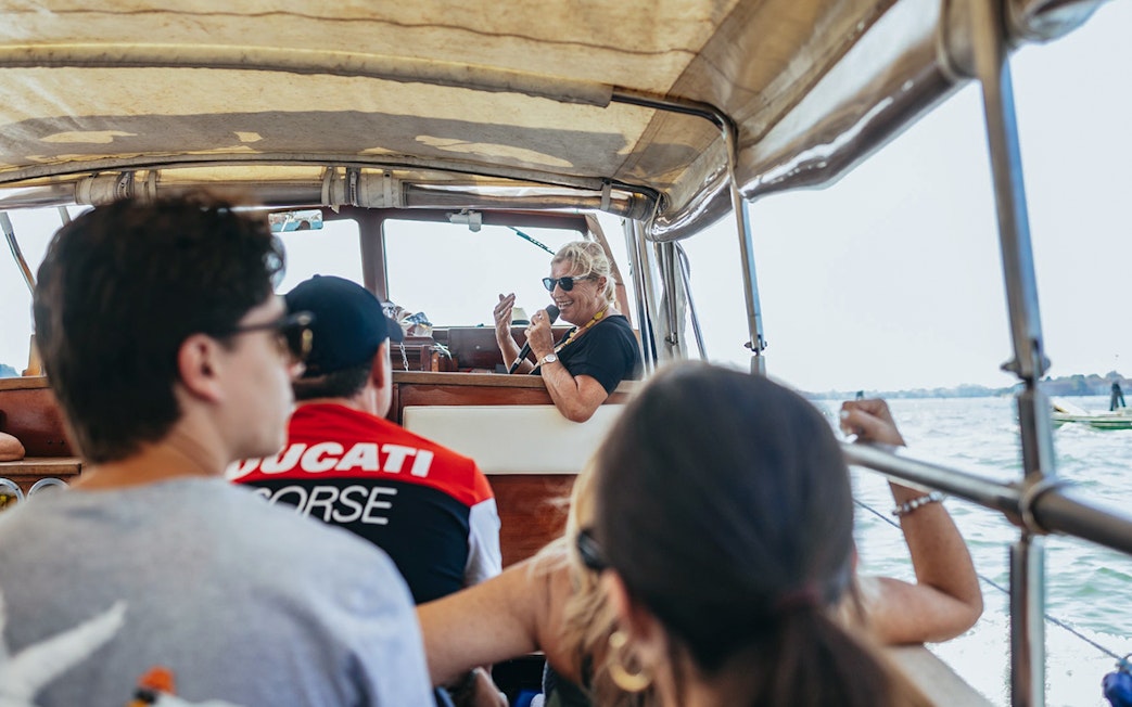 Boat tour guide giving live commentary to passengers on Murano and Burano Islands tour.