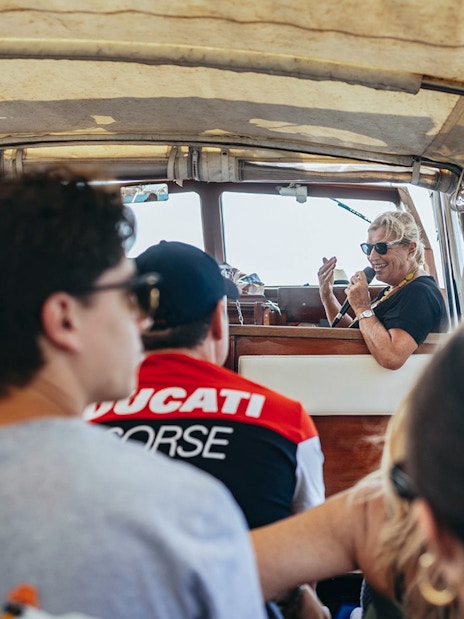 Boat tour guide giving live commentary to passengers on Murano and Burano Islands tour.