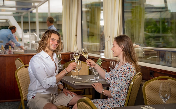 Couple toasting with wine on MS Kaiserin Elisabeth during Danube River cruise.