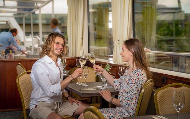 Couple toasting with wine on MS Kaiserin Elisabeth during Danube River cruise.