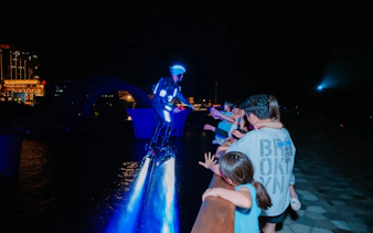 Performer in illuminated suit on water jetpack entertaining crowd at night, Phu Quoc.