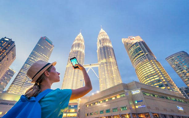 Tourist photographing Petronas Towers during Kuala Lumpur 10 Wonders Tour.