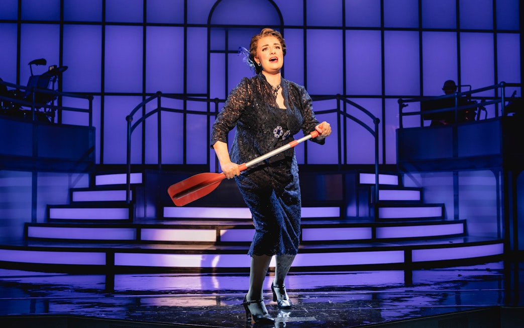 Performer on stage during Titanique Westend show holding a red oar.