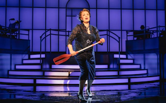 Performer on stage during Titanique Westend show holding a red oar.