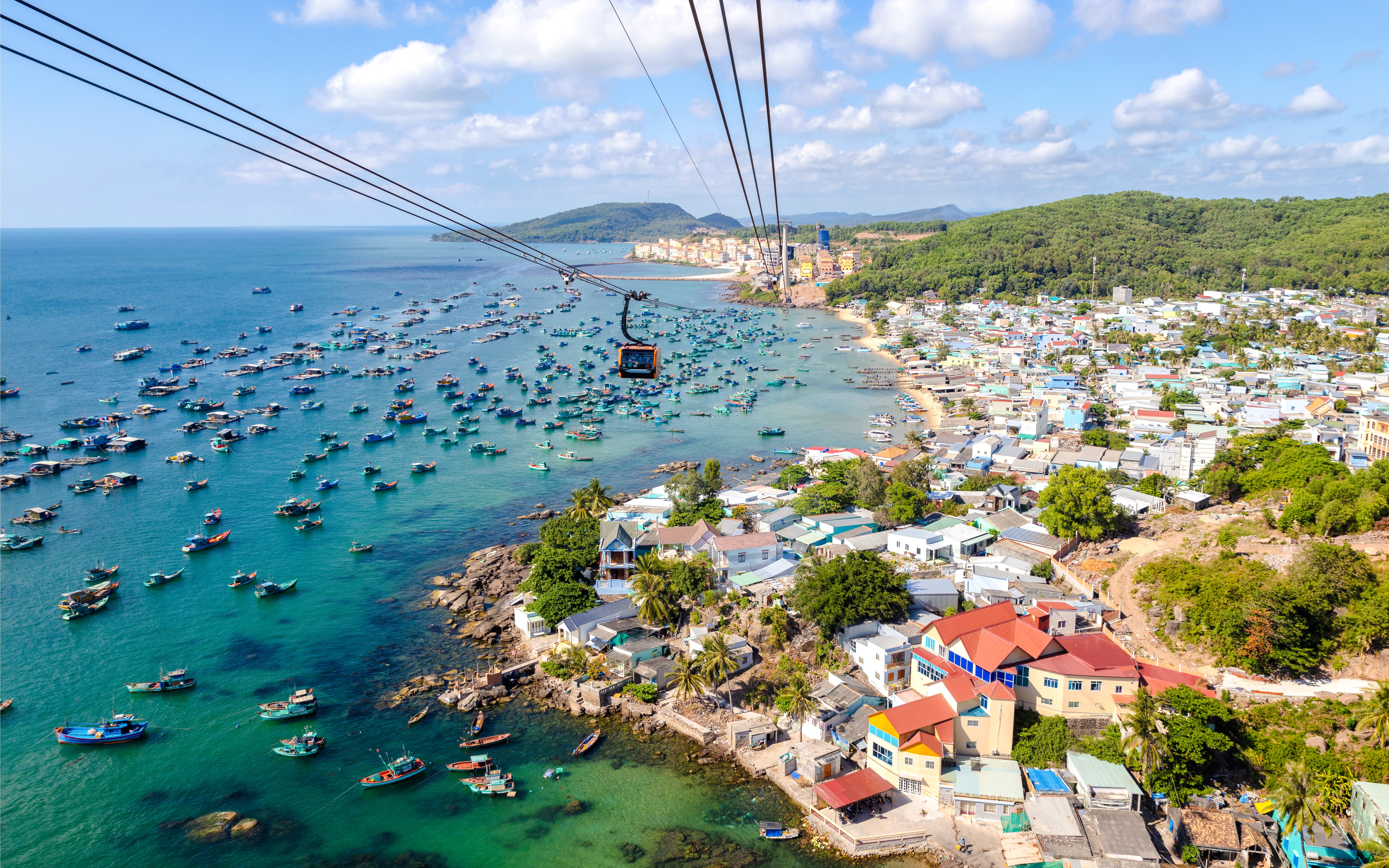 Aerial view of Phu Quoc island cable car ride over fishing boats and coastline, Vietnam.