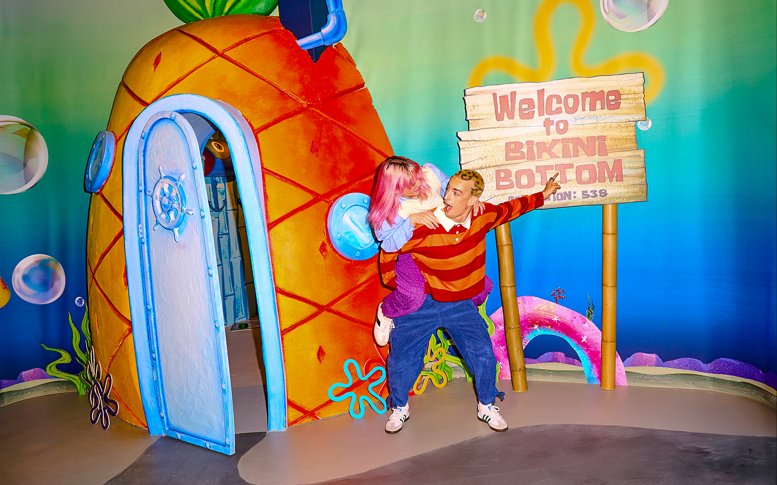 Visitors at SpongeBob Special, WONDR Experience, Amsterdam, near Bikini Bottom sign and pineapple house.