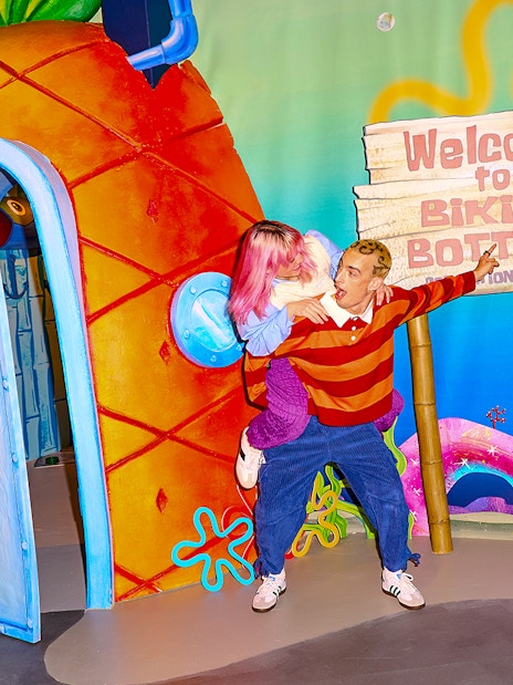 Visitors at SpongeBob Special, WONDR Experience, Amsterdam, near Bikini Bottom sign and pineapple house.