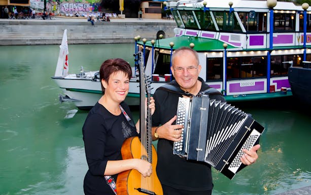 Musicians performing with guitar and accordion on a boat in Vienna.