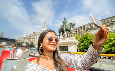 Woman taking selfie with King Dom Pedro statue in Porto.