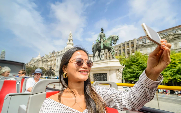 Woman taking selfie with King Dom Pedro statue in Porto.