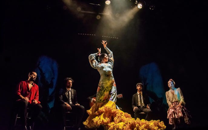 Flamenco dancer performing on stage at Teatro Flamenco Madrid with musicians seated around.