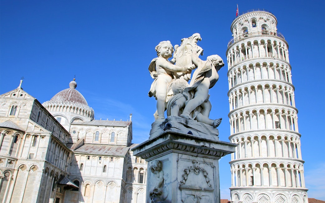 Leaning Tower of Pisa with nearby cathedral and statue in Pisa, Italy.