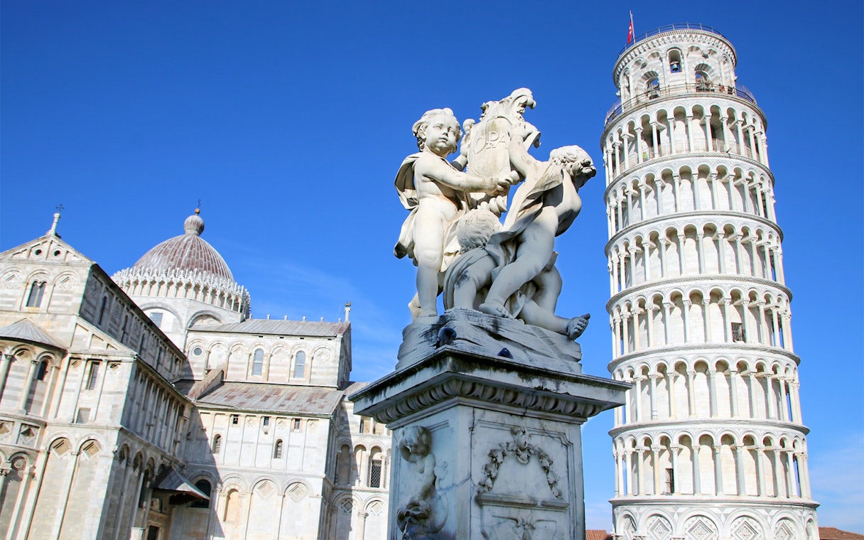 Leaning Tower of Pisa with nearby cathedral and statue in Pisa, Italy.