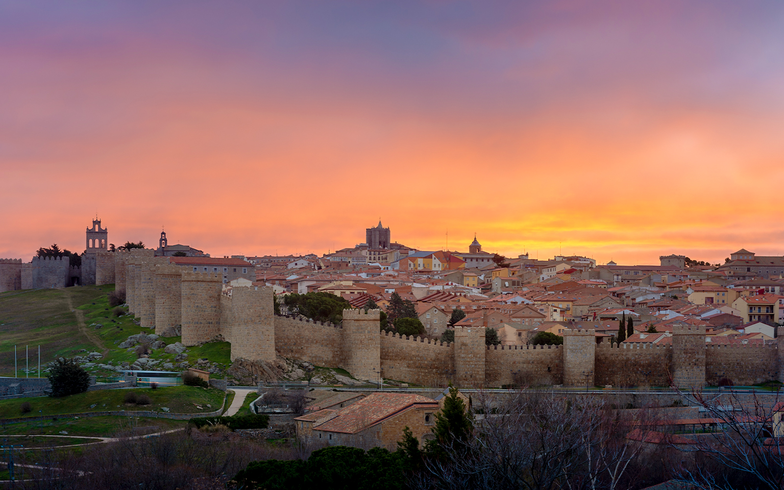 Panoramic view of Avila's medieval town walls at sunset from Los Cuatro Postes, Spain.